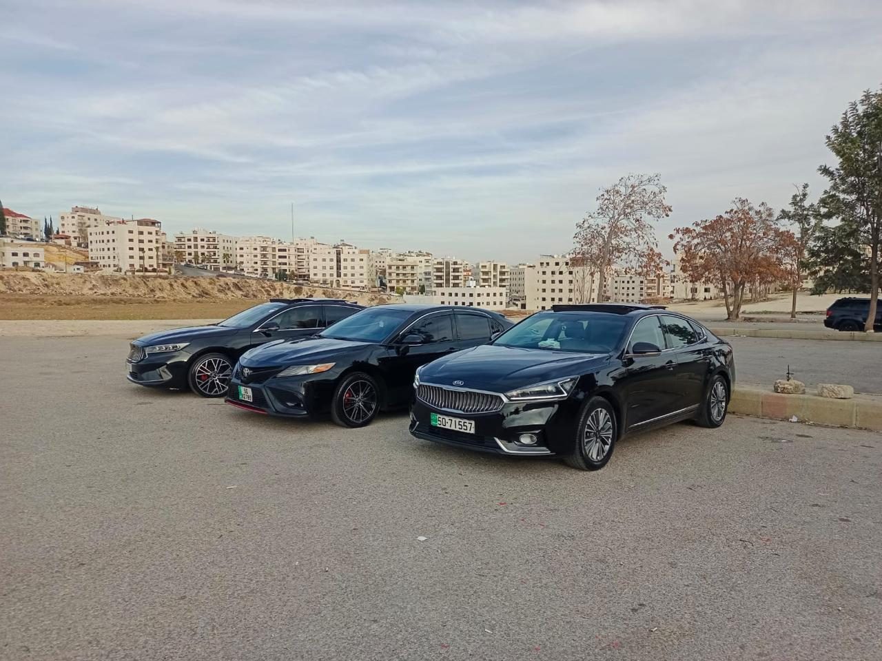 Black luxury sedans — Kia K7, Toyota Camry — in Amman, Jordan